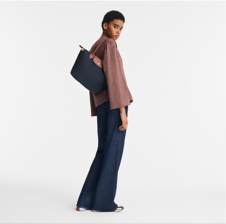 Person holding a black bag on a white background- black purse