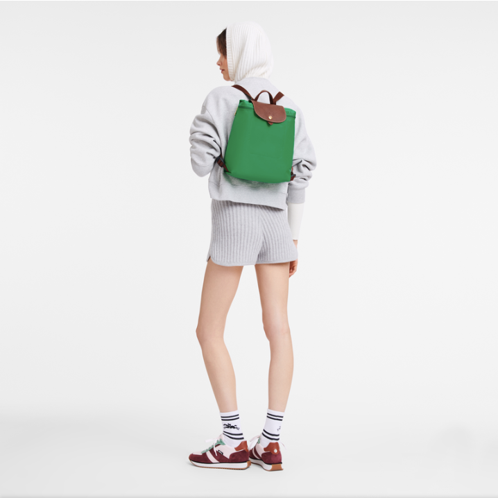 Person wearing a green longchamp backpack on a white background
