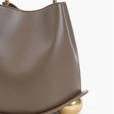 Close-up of gray ayla handbag with a gold handle on a white background