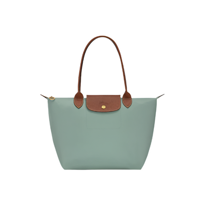 Green handbag with brown leather accents on a light gray background- green purse
