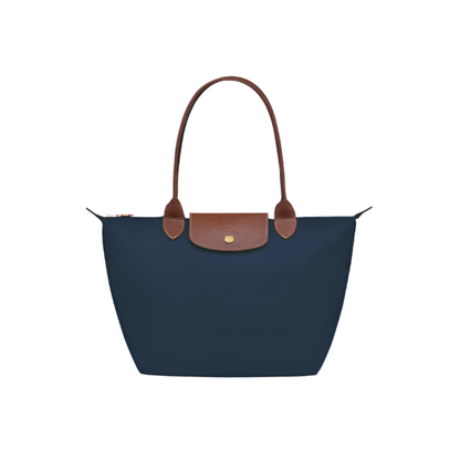Navy blue handbag with brown leather handle and trim on a light gray background- navy blue purse