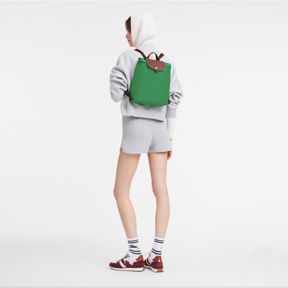 Person wearing a green longchamp backpack on a white background