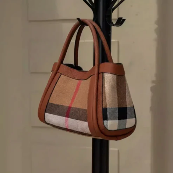 Plaid luno handbag hanging on a black coat rack against a neutral background