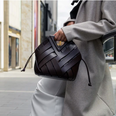 Person holding a black veya handbag in an urban setting