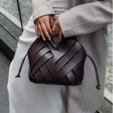 Person holding a brown veya handbag with a neutral background