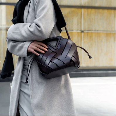 Person holding a brown veya leather handbag against a neutral background