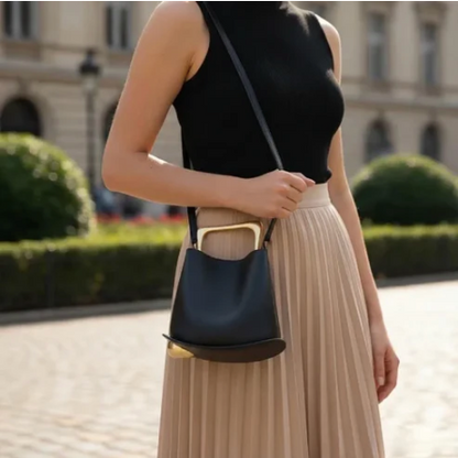 Woman holding a black ayla handbag with a blurred background of a building and greenery