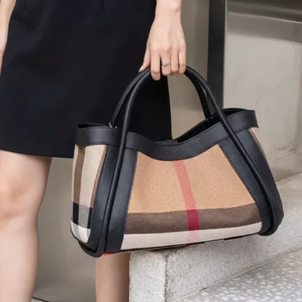 Person holding a black luno handbag with black handles and trim.